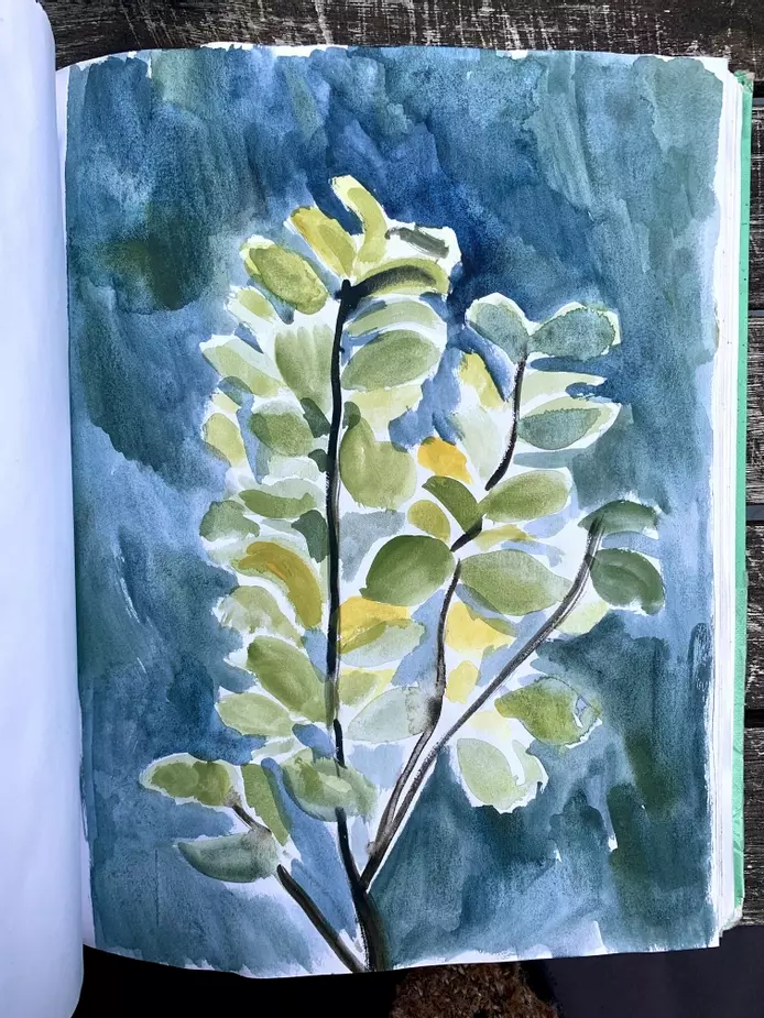 a sketchbook page of a painting of a tree. The close up painting shows the wide green curved leaves against a dark blue background 